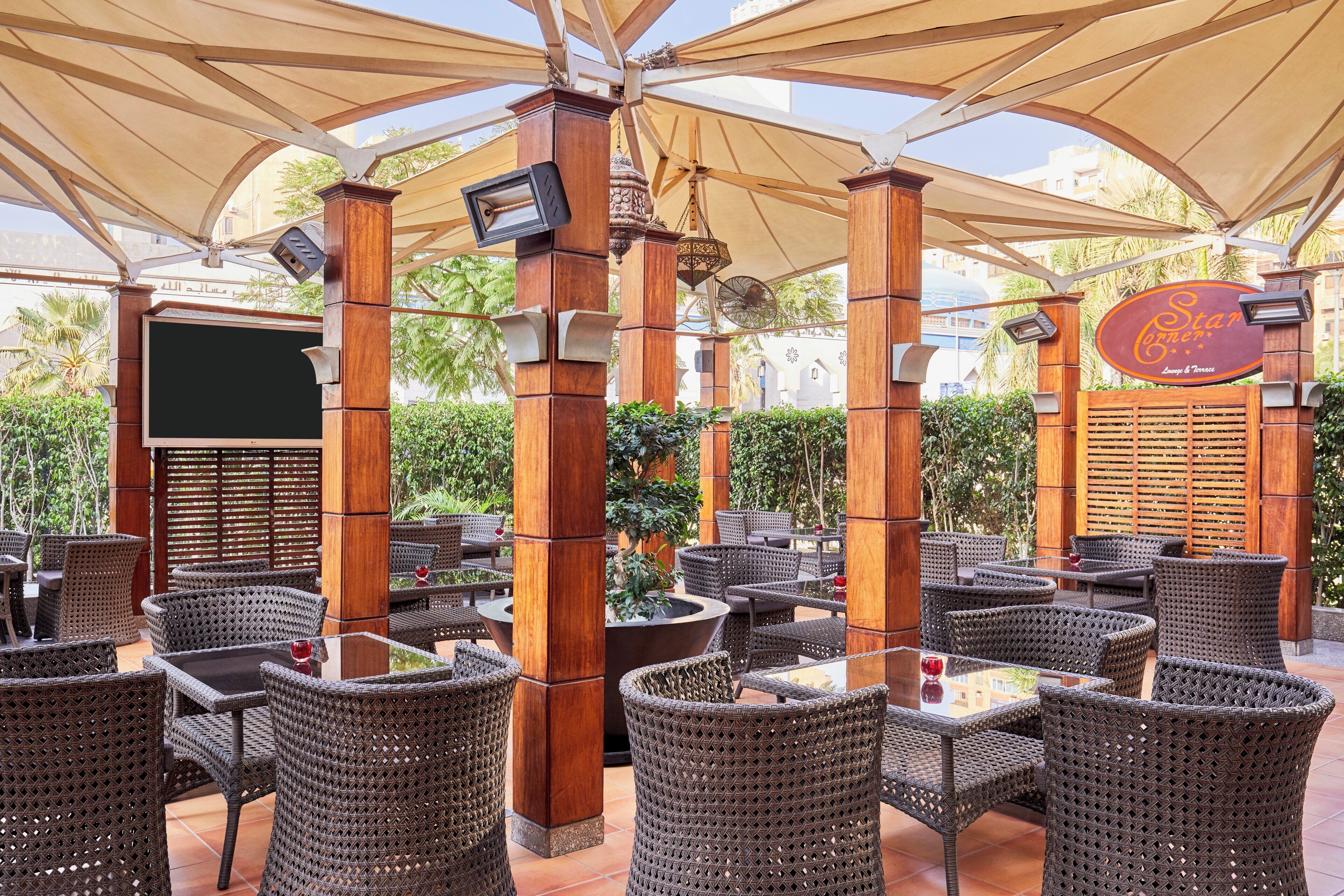 An outdoor seating area with wicker furniture and a covered section with a sign for 'Star Corner Lounge & Terrace'.