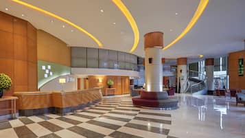 Un vestíbulo de hotel con piso a cuadros, una recepción y una escalera.