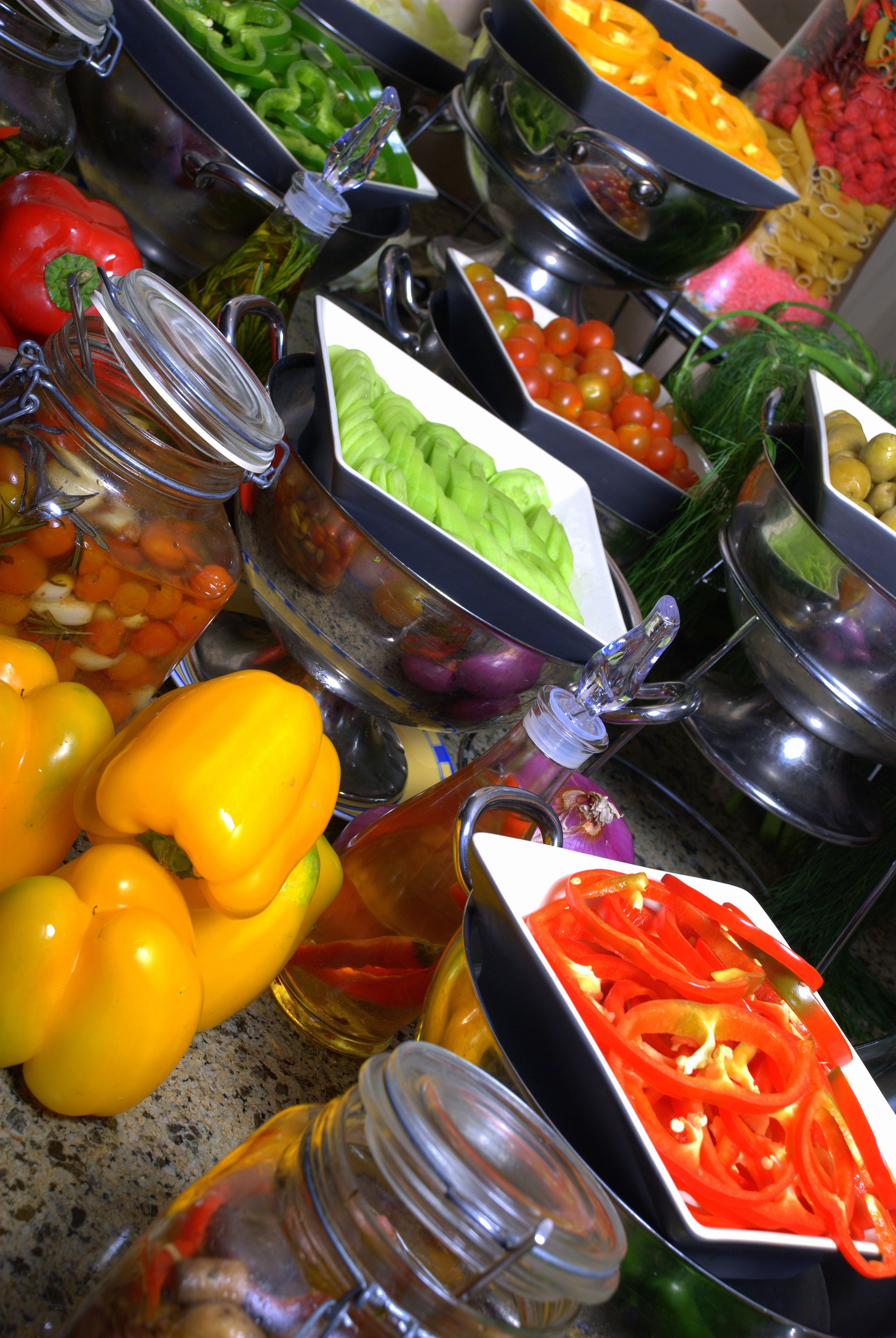 A buffet with various food items including sliced vegetables, pasta, and salads.