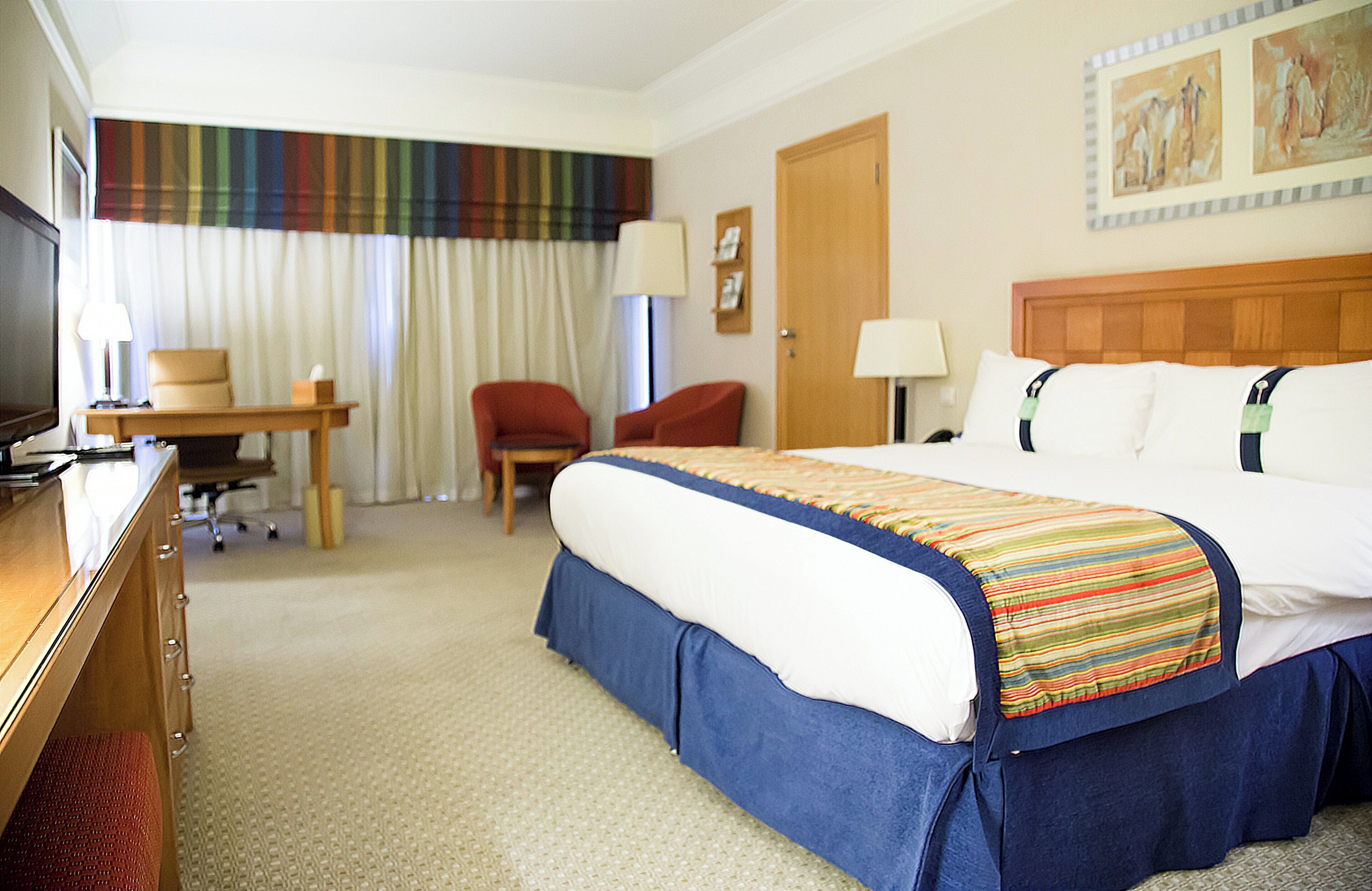 Una habitación de hotel con una cama, un escritorio, una silla, un televisor y una puerta.