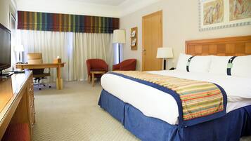 Una habitación de hotel con una cama, un escritorio, una silla, un televisor y una puerta.