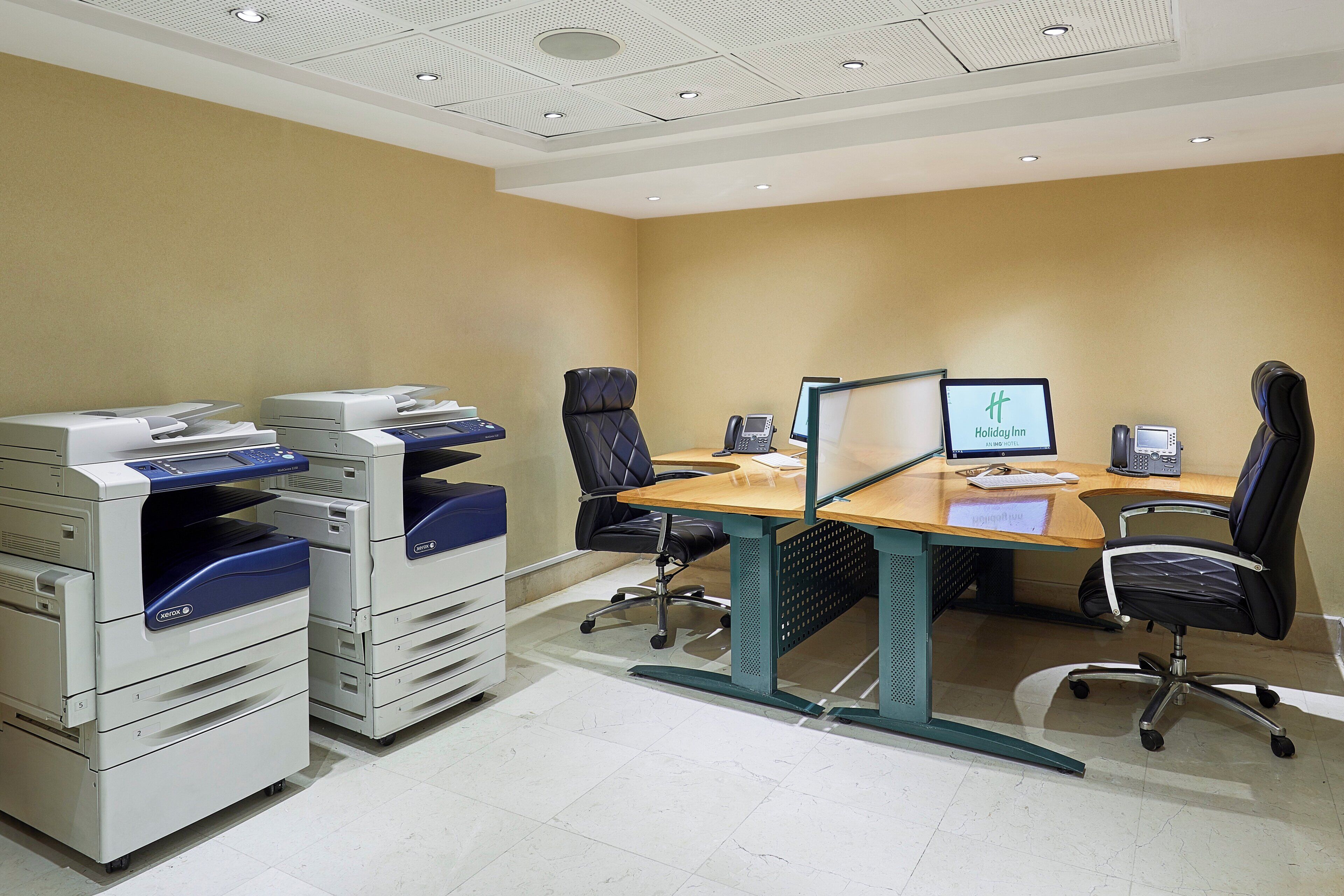 A conference room with a desk, chairs, a computer, and Xerox printers.