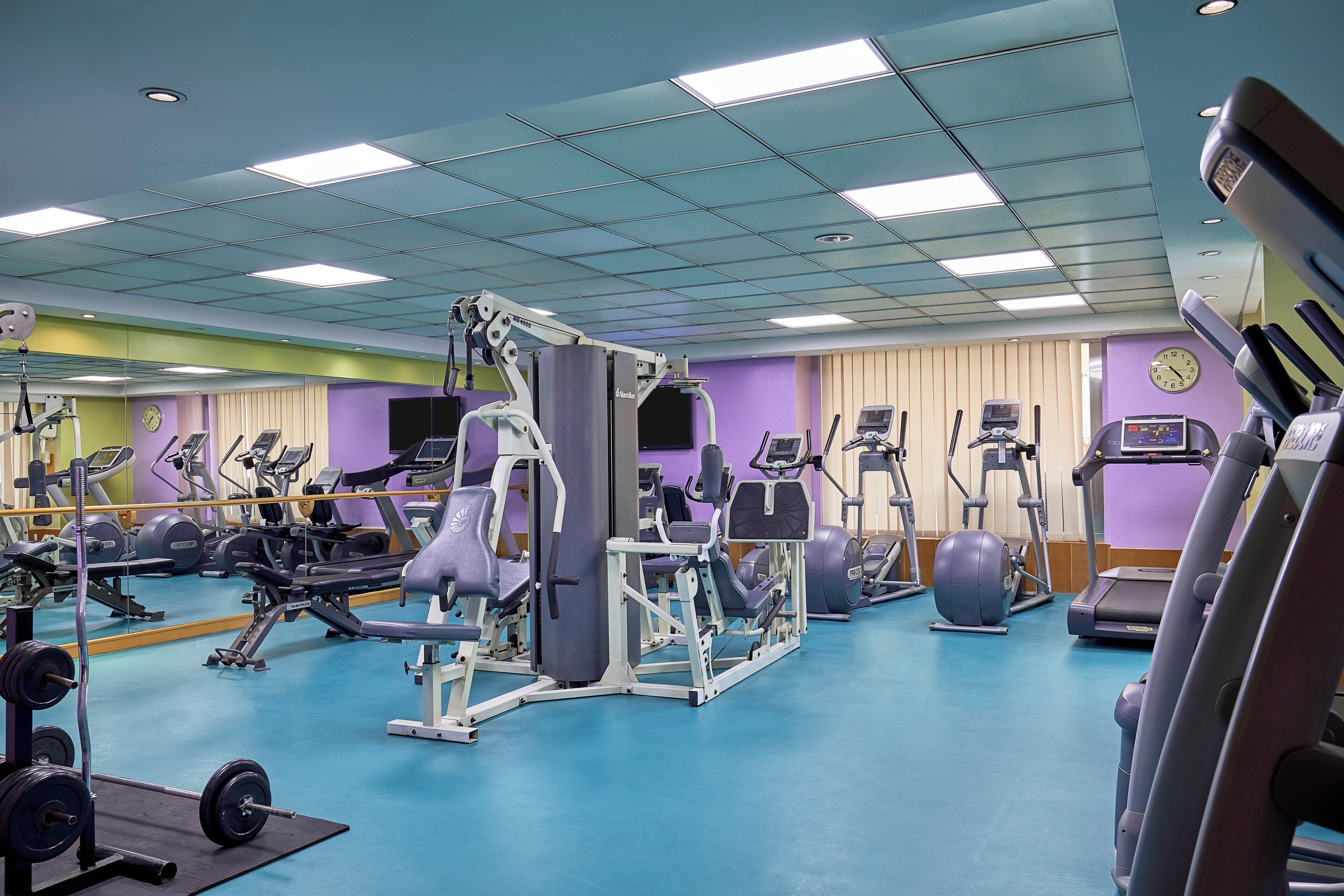A gym with various exercise equipment, including treadmills, stationary bikes, and weight machines.