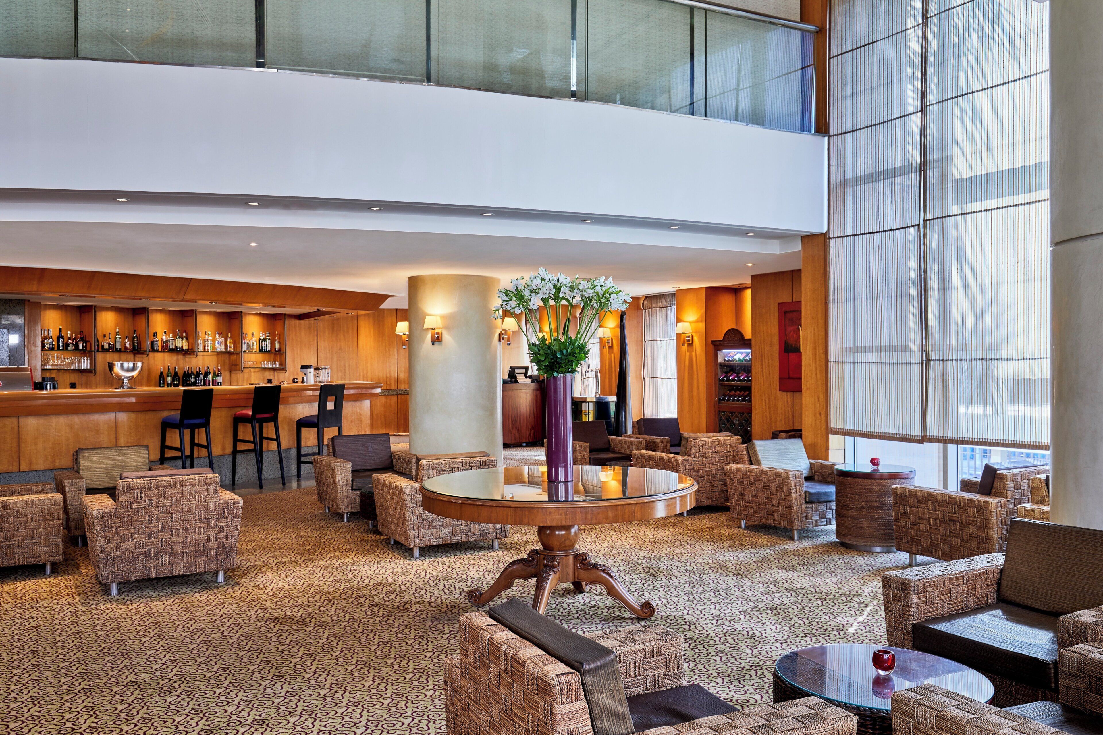 A hotel lobby with a bar area, seating arrangements, and a large window providing natural light.