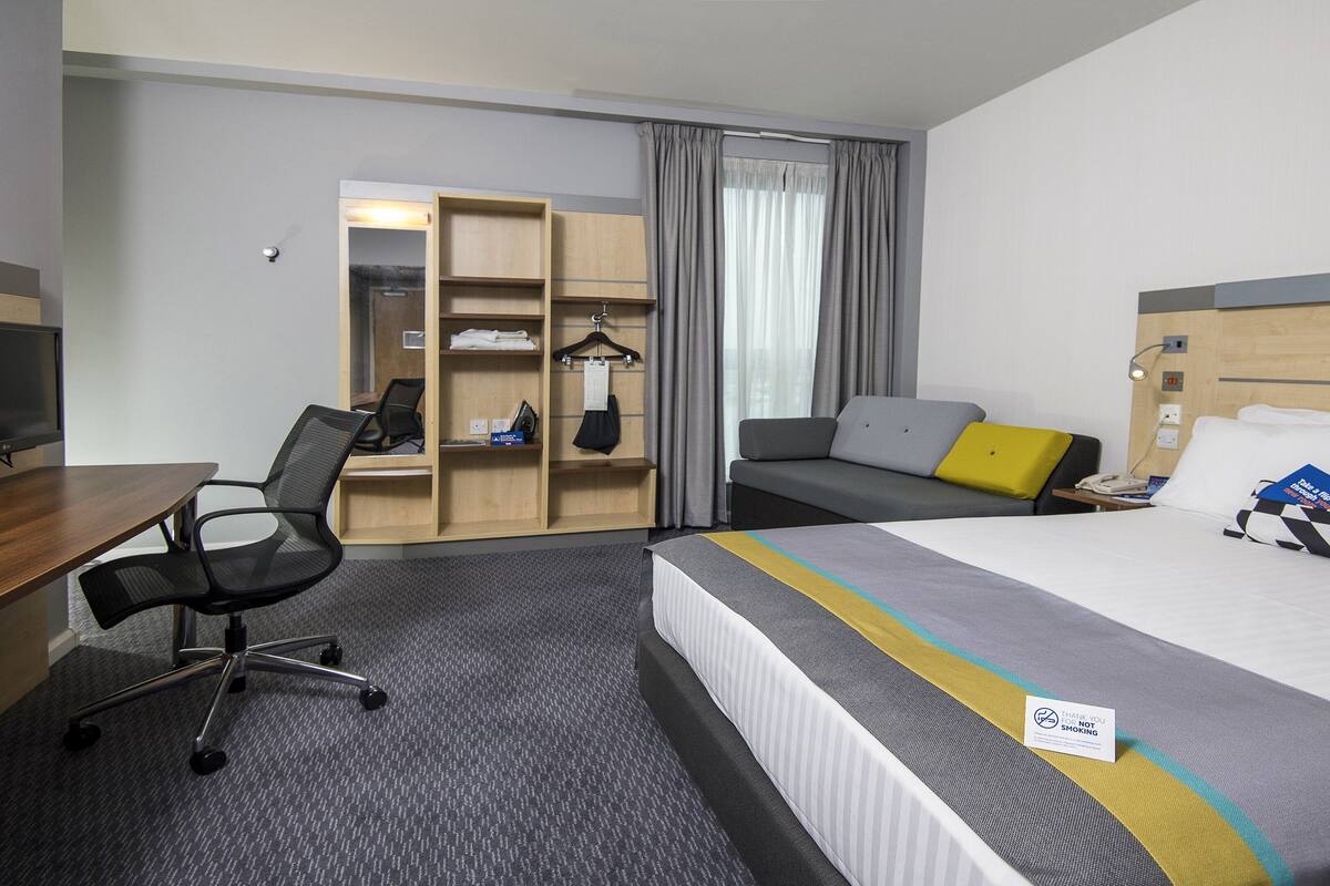 Une chambre d’hôtel équipée d’un lit, d’un bureau, d’une chaise, d’une armoire et d’un téléviseur.