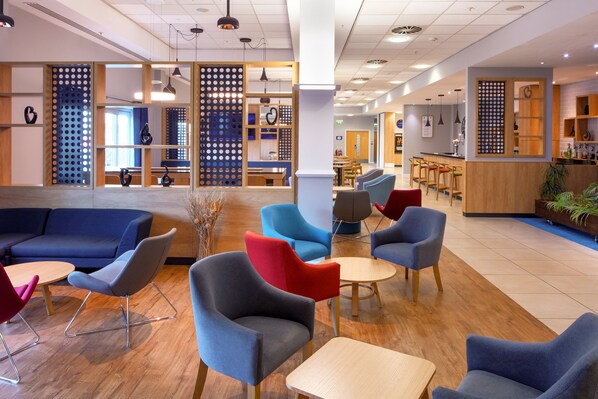 A modern lounge area with sofas, chairs, and a bar. - Holiday Inn Express Hull City Centre by IHG (Hull)
