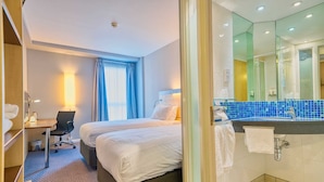 A hotel room with two beds, a desk, a chair, a bathroom with a sink and mirror, and a view of the outside. - Holiday Inn Express Hull City Centre by IHG (Hull)