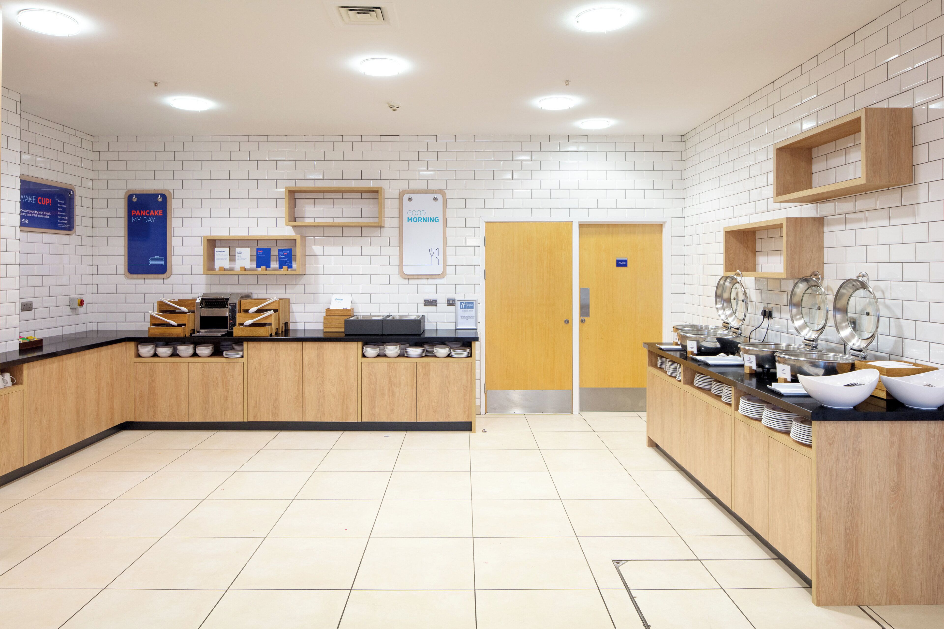 Un espace cuisine moderne avec un bar pour prendre le petit-déjeuner, une machine à café et un panneau indiquant « Bonjour ».