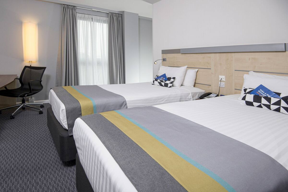 Une chambre d’hôtel avec deux lits, un bureau, une chaise, une télévision et un téléphone.