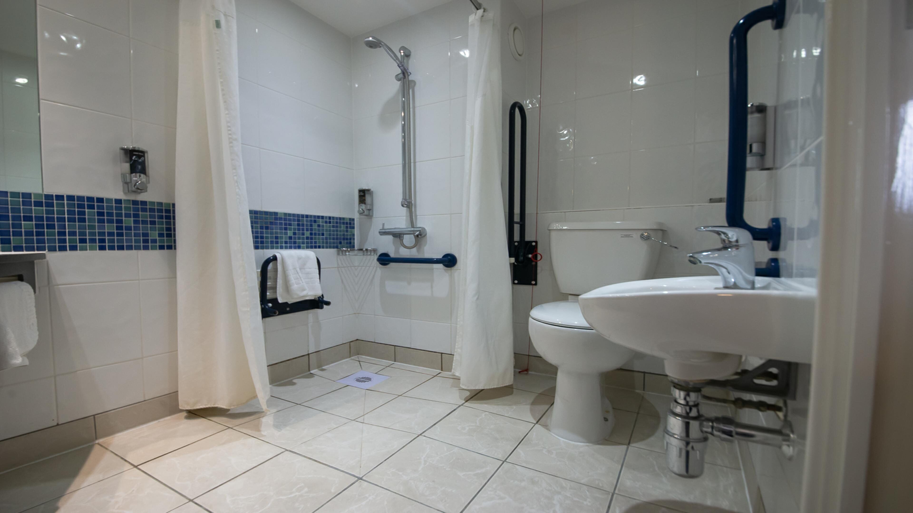 Een moderne badkamer met douche, toilet en wastafel.