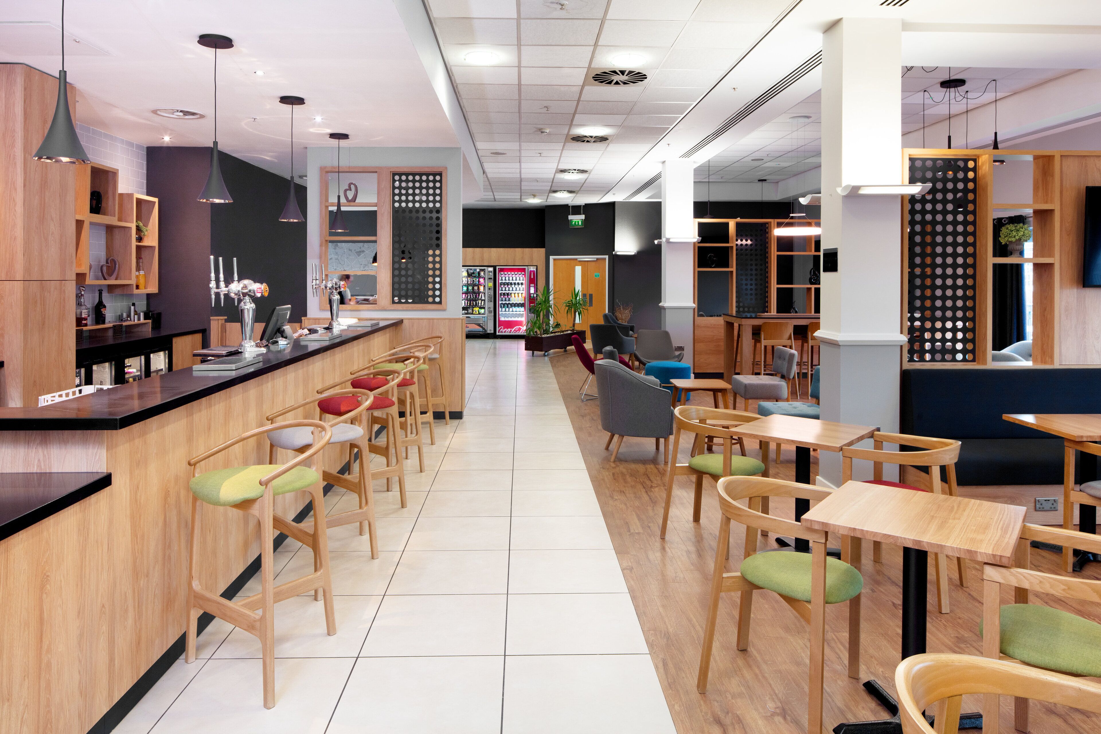A modern cafe with wooden furniture, a counter, and a seating area with tables and chairs.