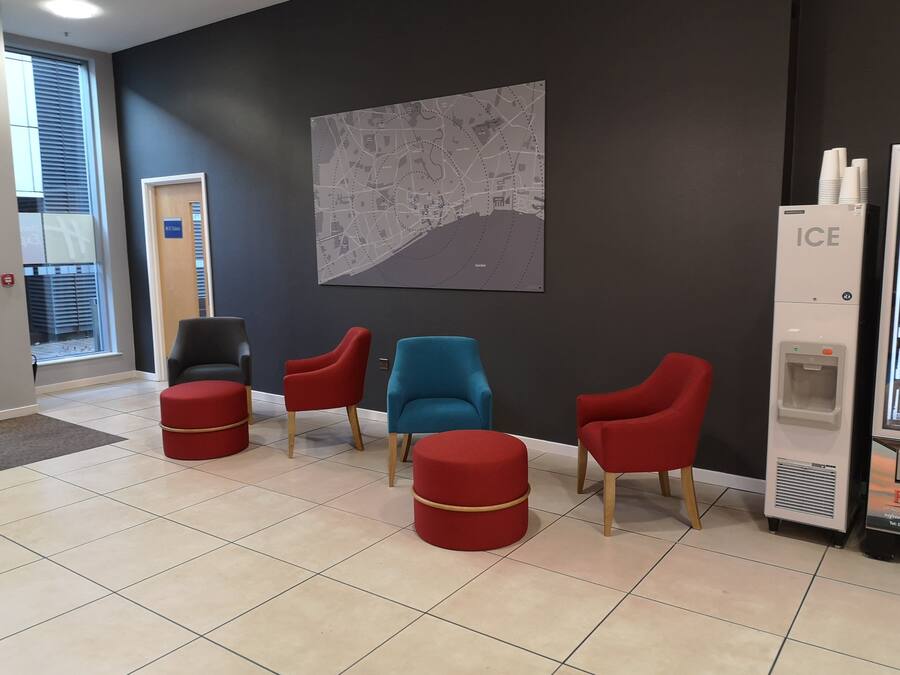 Une salle d’attente avec une carte affichée au mur, un distributeur automatique et une porte portant l’inscription « Serviettes ».