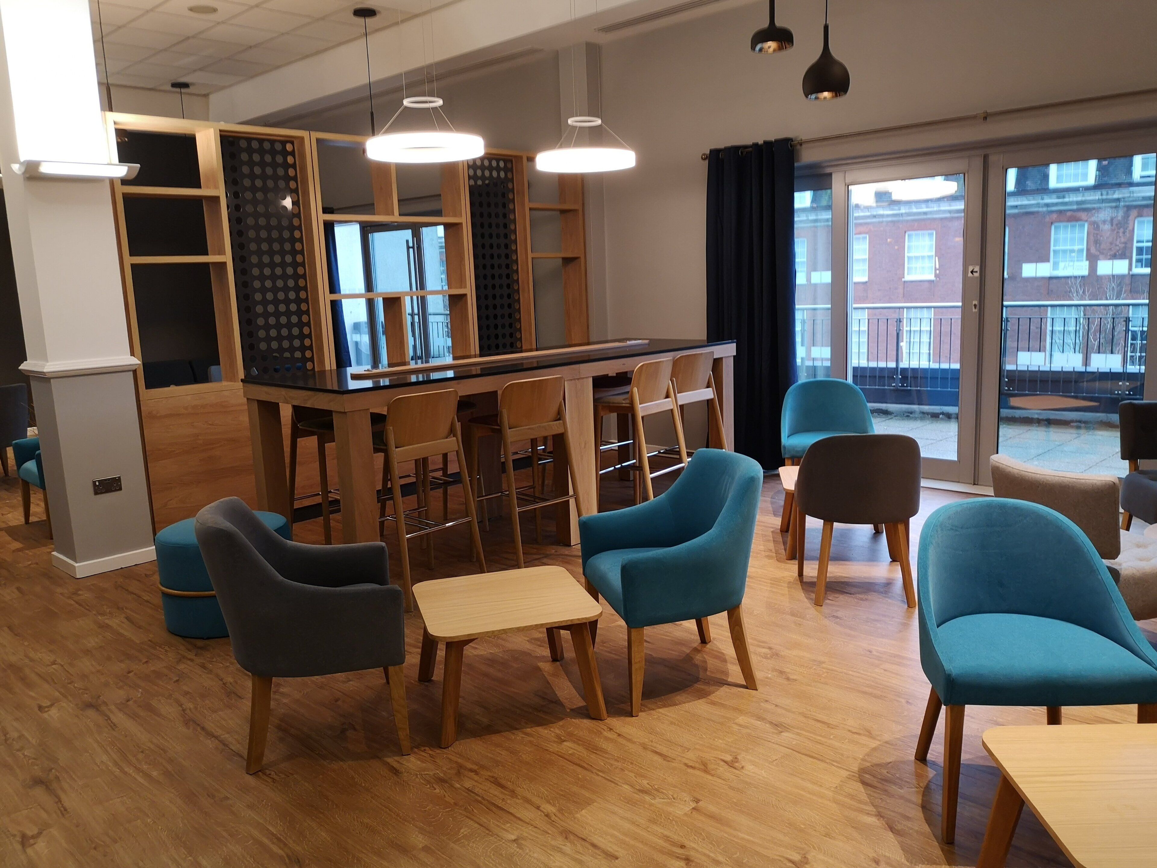Un área de bar moderna con mobiliario de madera y vistas al exterior.