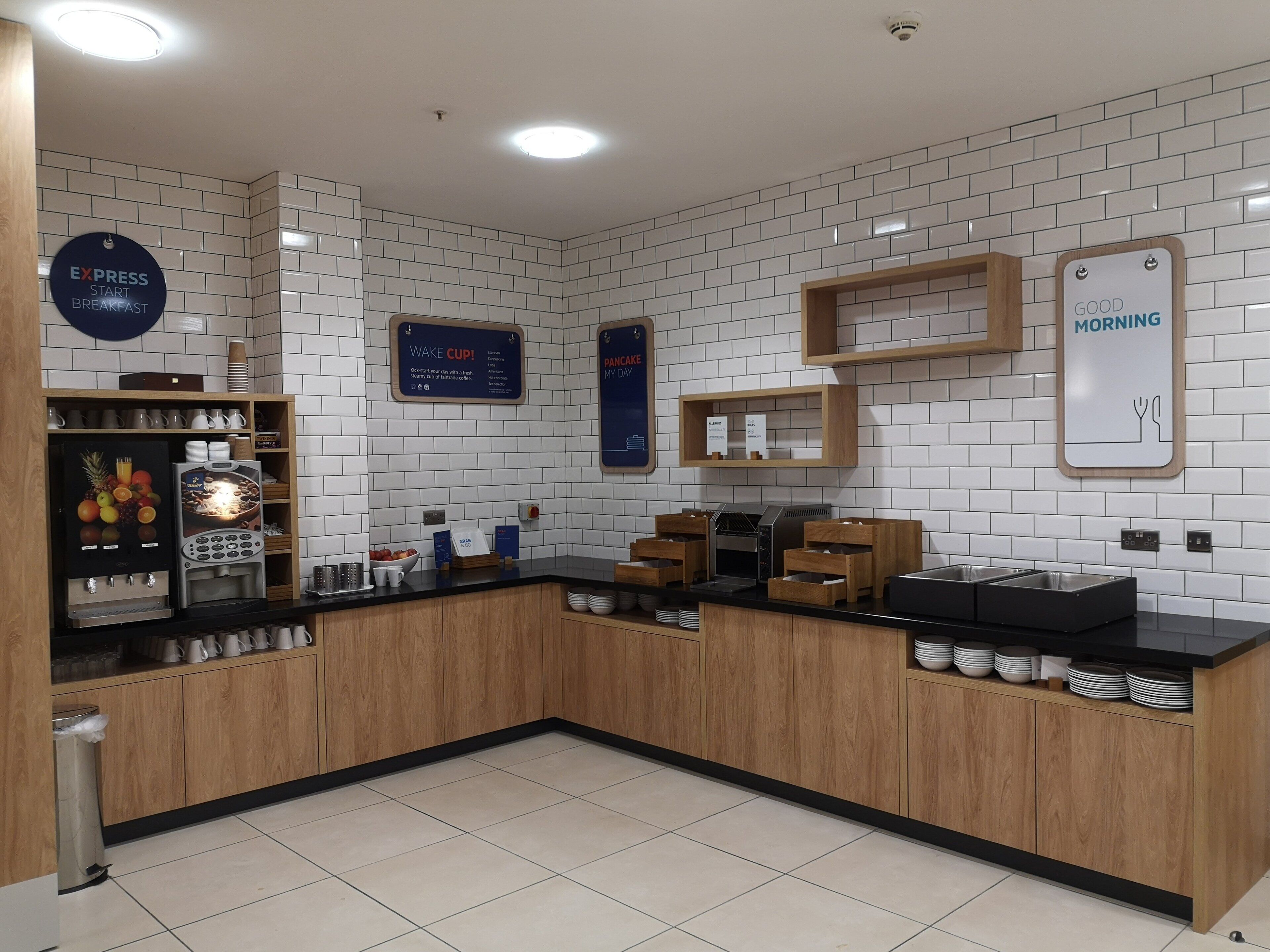 A modern kitchen area with a coffee station, a wake-up sign, and a breakfast sign.
