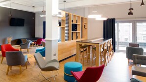 A modern lounge area with a variety of seating options, a bar, and a large window offering a view of the city. - Holiday Inn Express Hull City Centre by IHG (Hull)