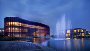 Ein modernes Gebäude mit einer geschwungenen Fassade und einem Wasserspiel davor.