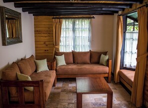 A cozy living room with a wooden sofa, a wooden coffee table, and a stone-tiled floor.