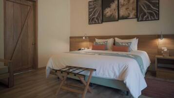 Quarto com cama de madeira, um banquinho, mesa de cabeceira e decoração na parede.