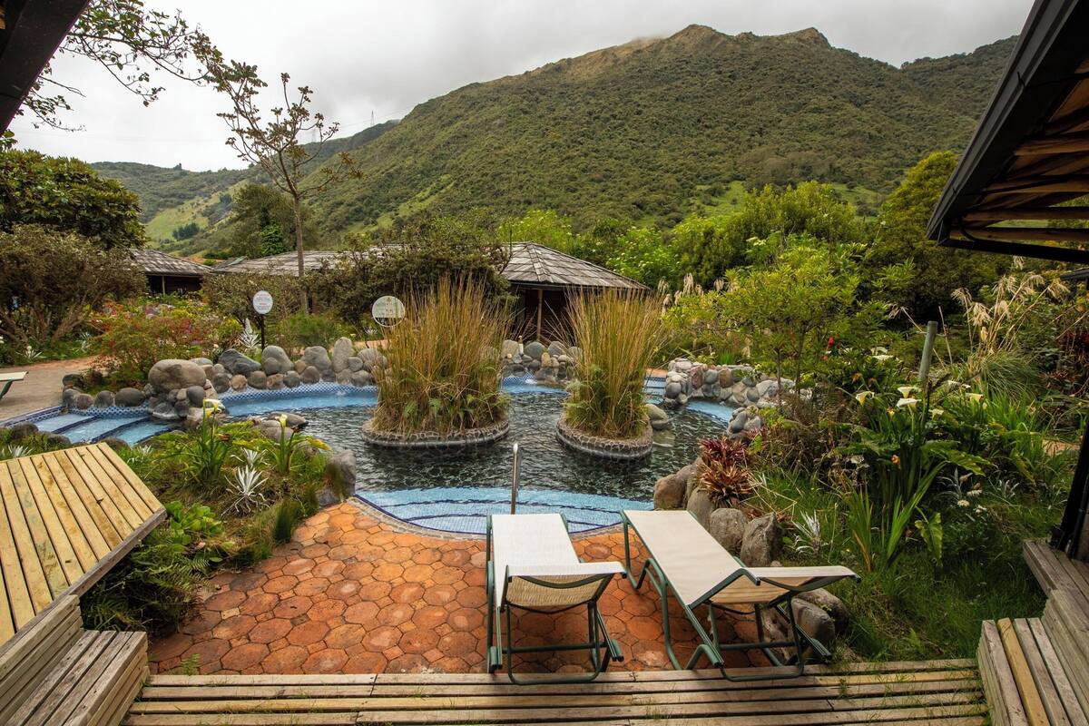 A serene outdoor area with a small pond, wooden deck, and seating.