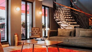 A modern living room with a sofa, a coffee table, and a staircase with ornate railings. - Hive Nápoles By G Hotels (Mexico City)