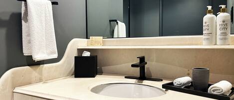 A bathroom with a sink, mirror, towel rack, and toiletries.