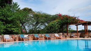 Una piscina con sillones de descanso y una pérgola.