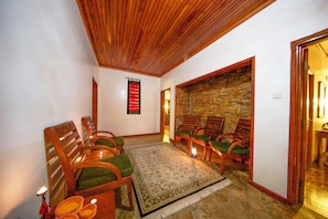 Traditional design meets comfort in this inviting room, featuring a wooden ceiling, stone wall, and plush chairs.