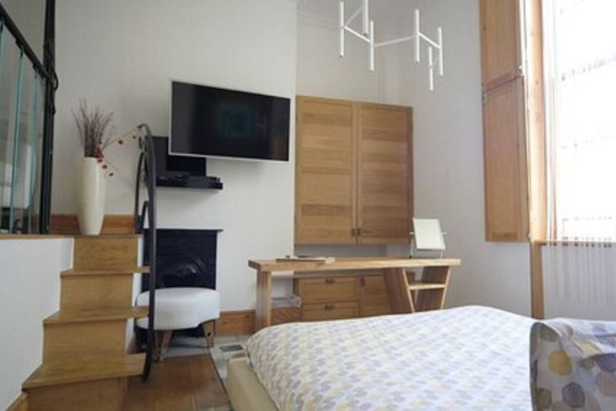 A bedroom with a bed, a desk, a chair, a TV, and a wardrobe.