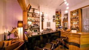 A bar area with wooden furniture, a counter, and shelves stocked with bottles. - Una (BRIGHTON)