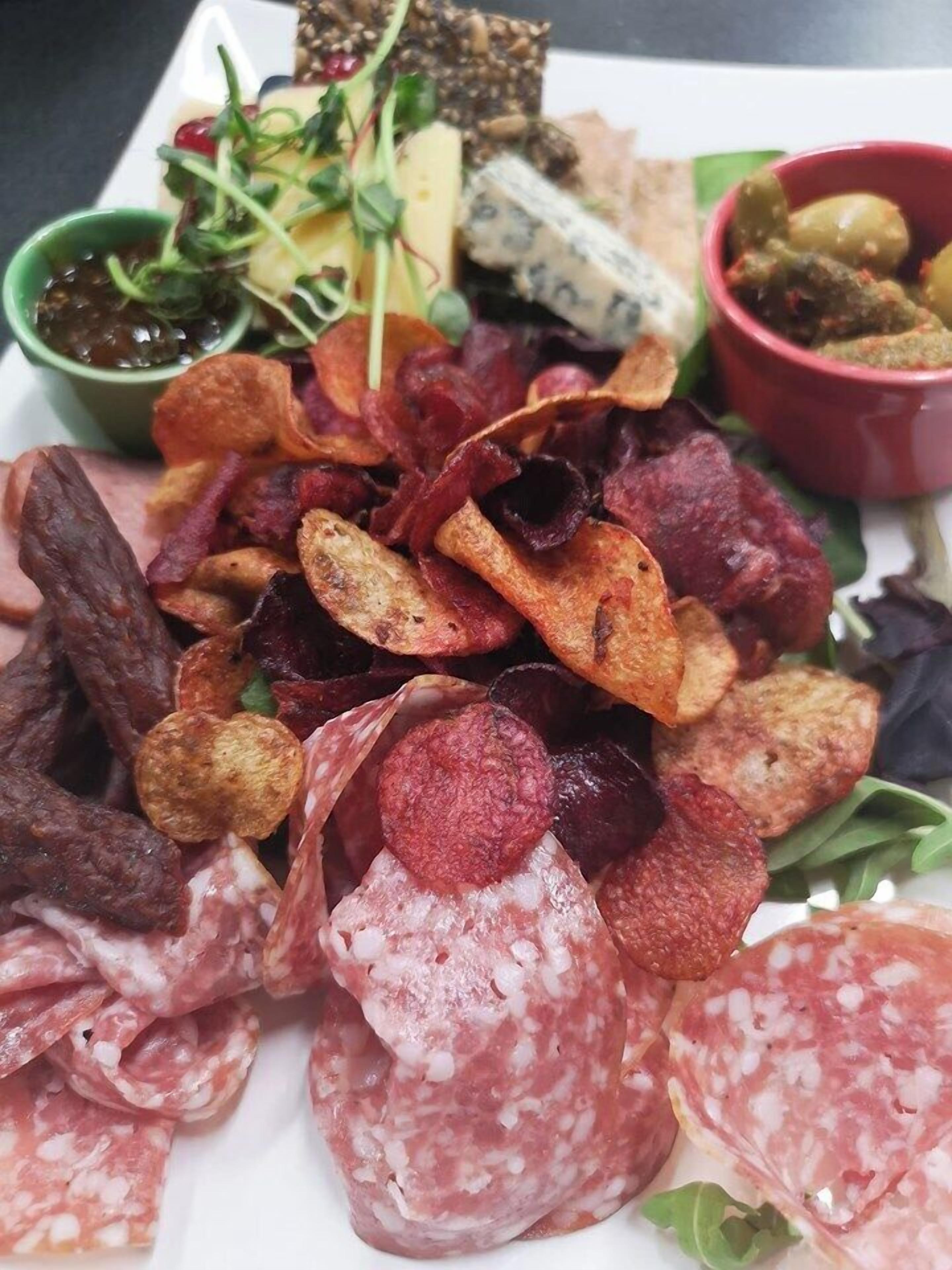 A charcuterie board with various meats, cheeses, and accompaniments.