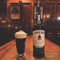 Una botella de Jameson Irish Whiskey Triple Destilado y una cerveza sobre una mesa de madera.