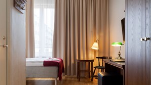 A hotel room with a bed, a desk with a lamp, and a wardrobe. - Hotel Bishops Arms Kristianstad (Kristianstad)