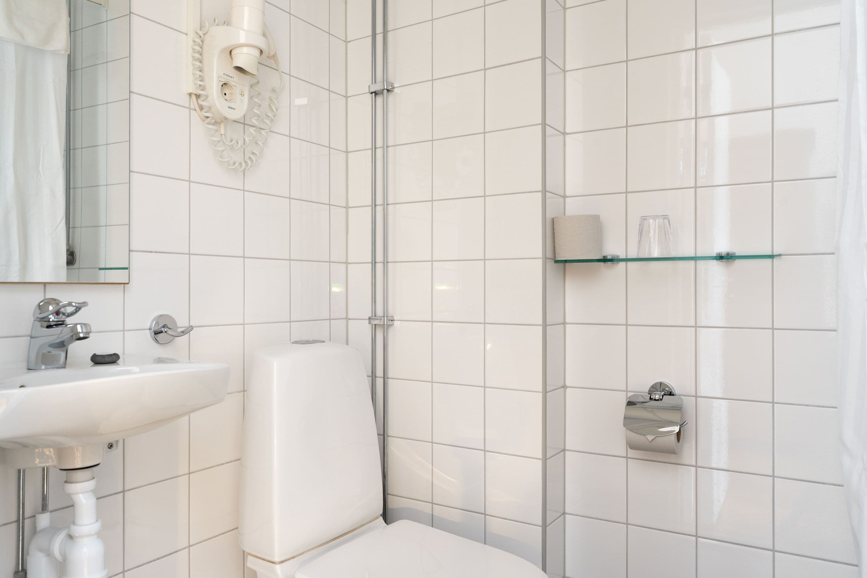 Un baño moderno con lavamanos, inodoro y ducha blancos.