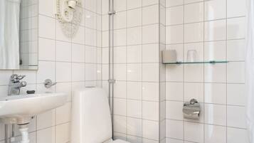 Un baño moderno con lavamanos, inodoro y ducha blancos.