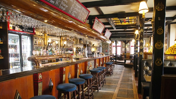 A bar area with stools, a bar counter, and a menu board. - Hotel Bishops Arms Kristianstad (Kristianstad)