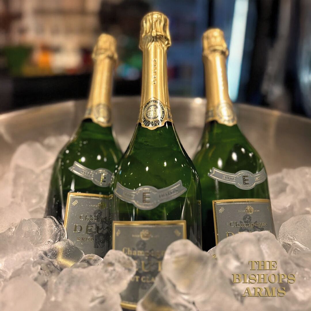 Trois bouteilles de champagne dans un récipient métallique, entourées de glaçons.