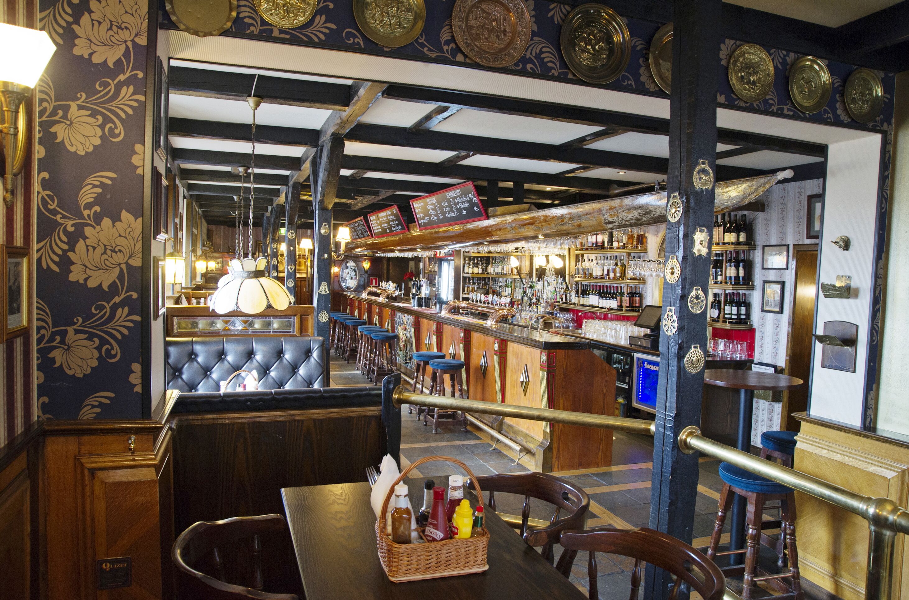 A bar area with a counter, stools, and a variety of bottles.