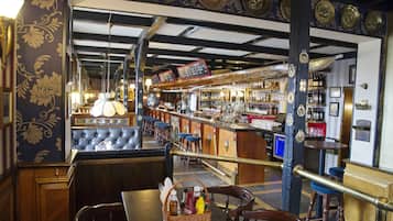 A bar area with a counter, stools, and a variety of bottles.