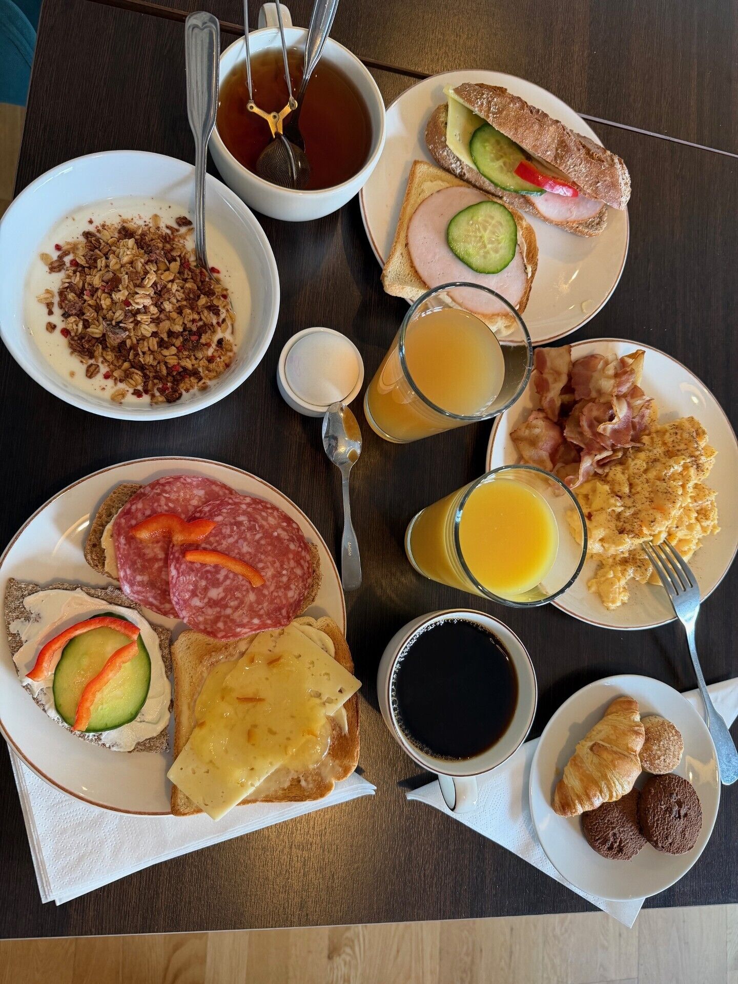A breakfast table with various dishes including toast, eggs, bacon, and pastries.