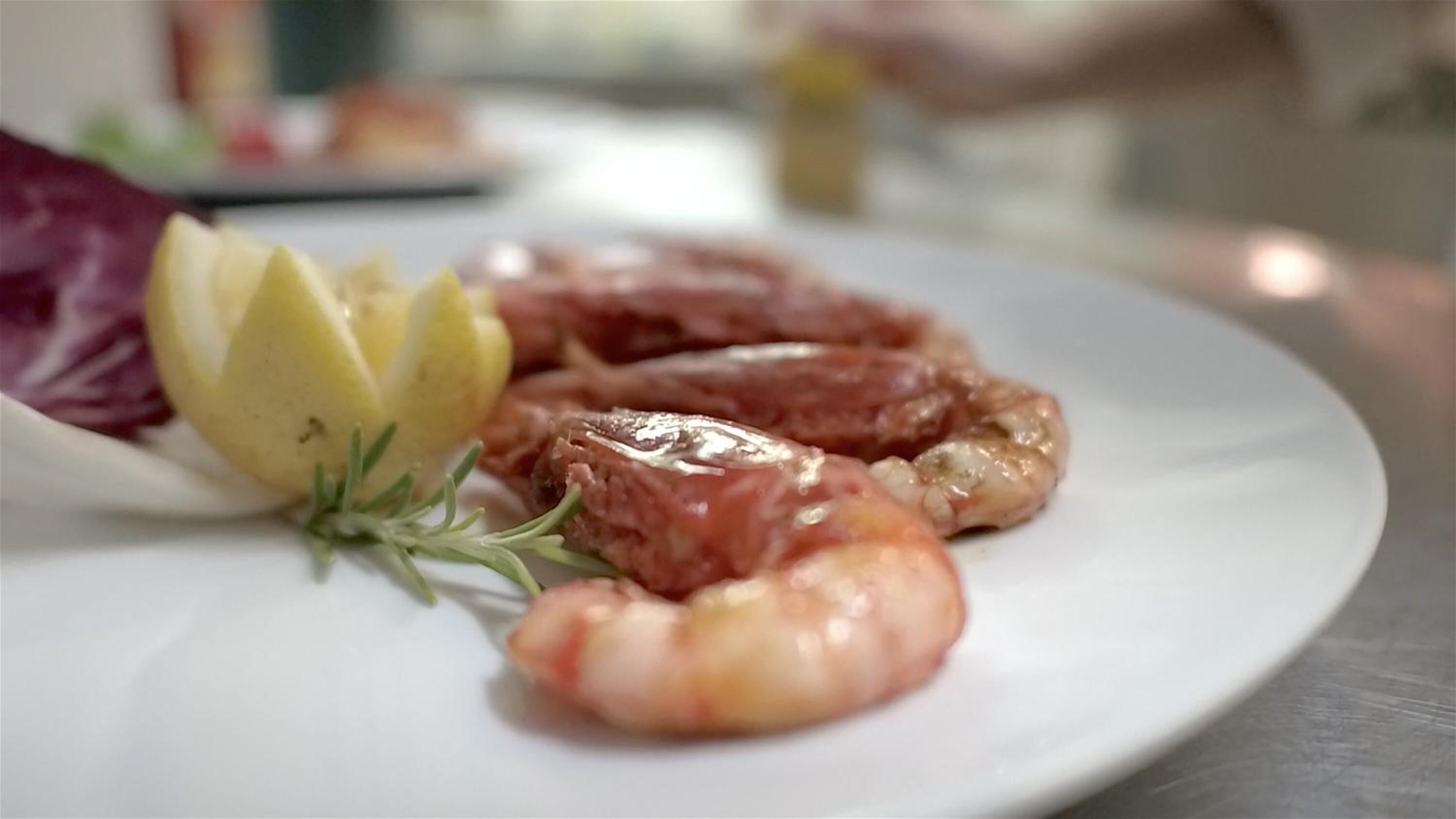 Un plato con camarones y bistec, adornado con hierbas y rodajas de limón.