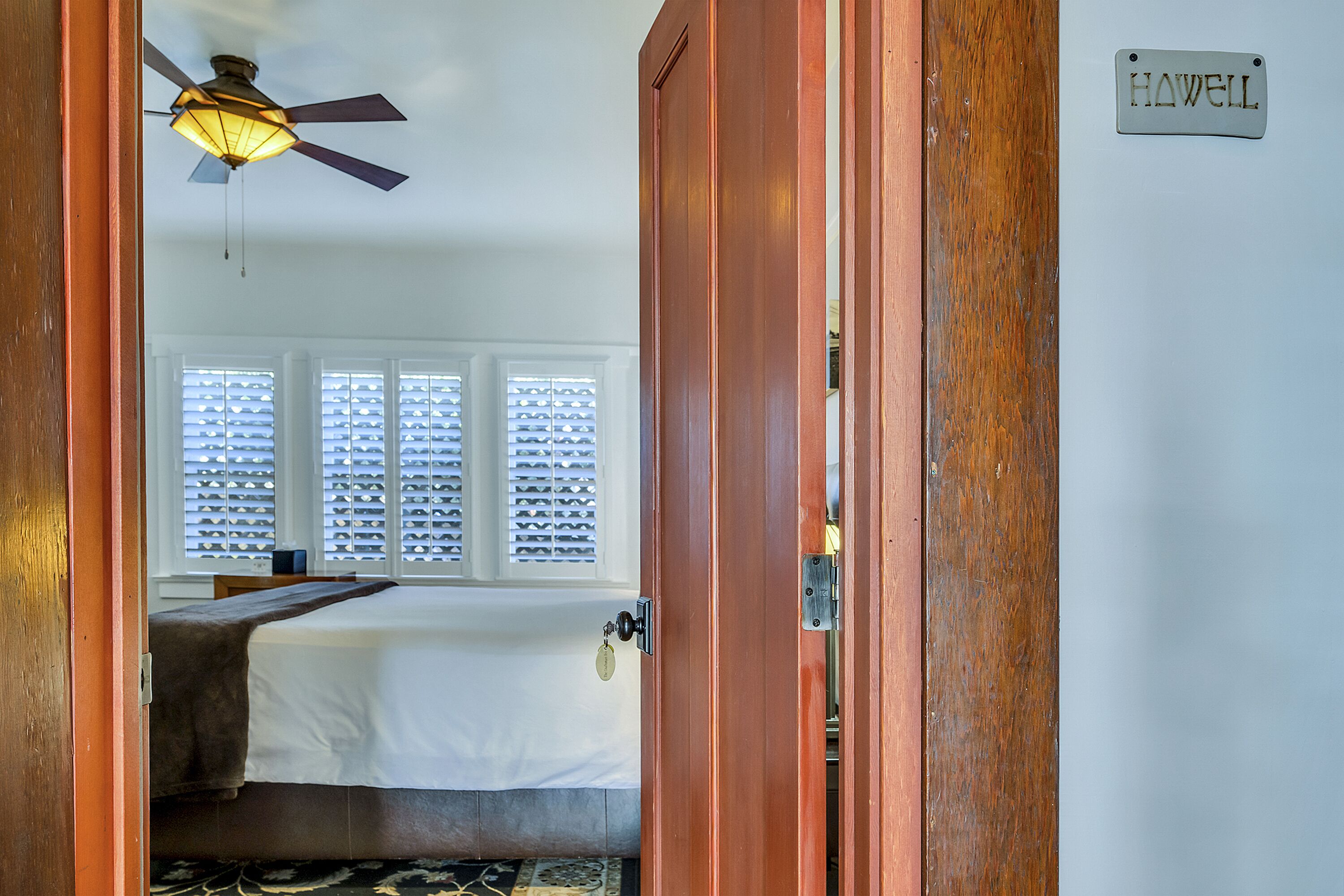 A bedroom with a bed, a ceiling fan, and a window with blinds.