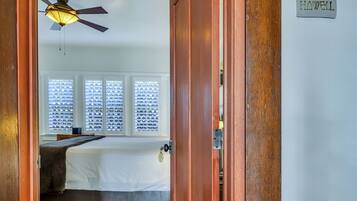 A bedroom with a bed, a ceiling fan, and a window with blinds.