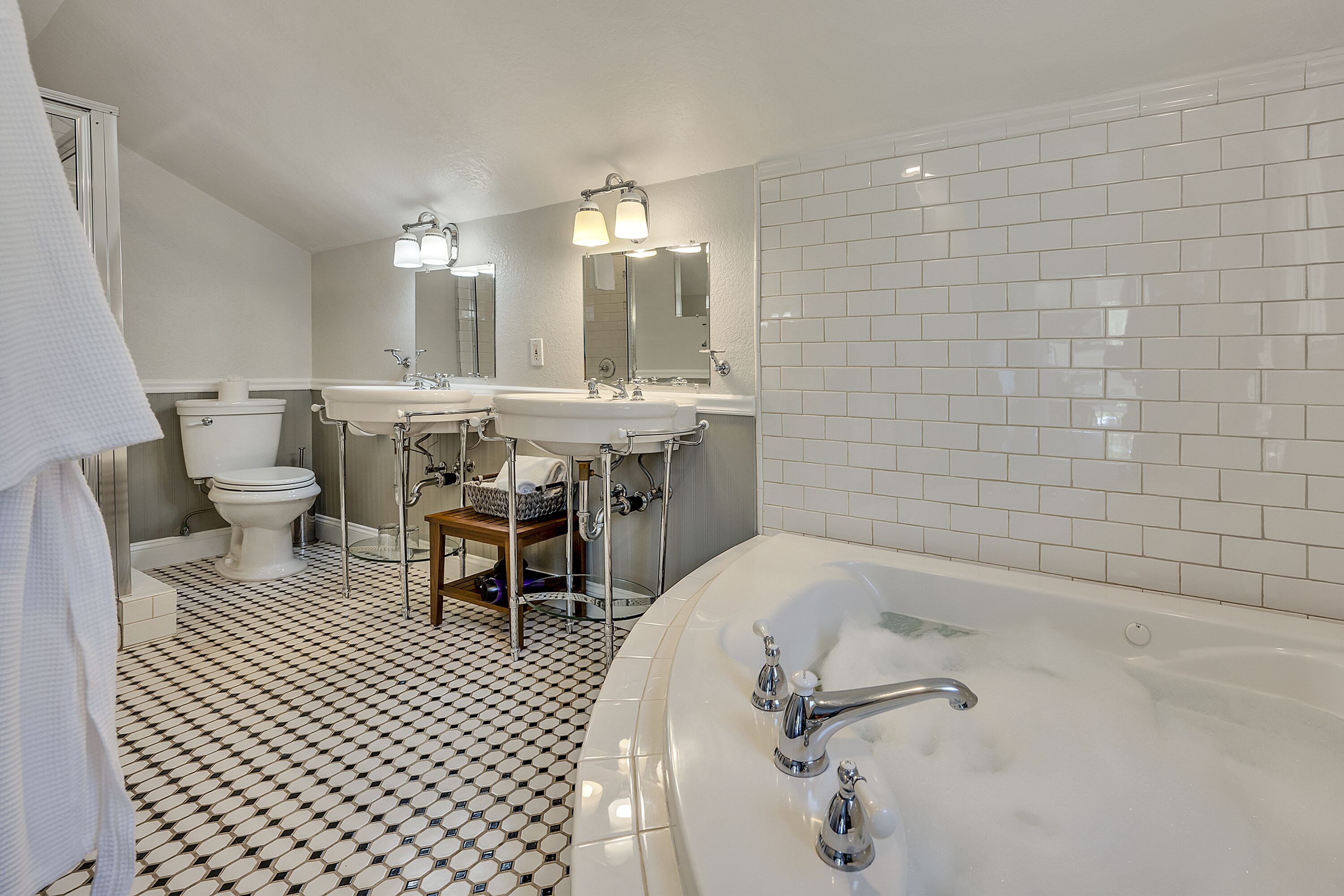 Ein Badezimmer mit einer großen Badewanne, zwei Waschbecken, einer Toilette und einem Spiegel.