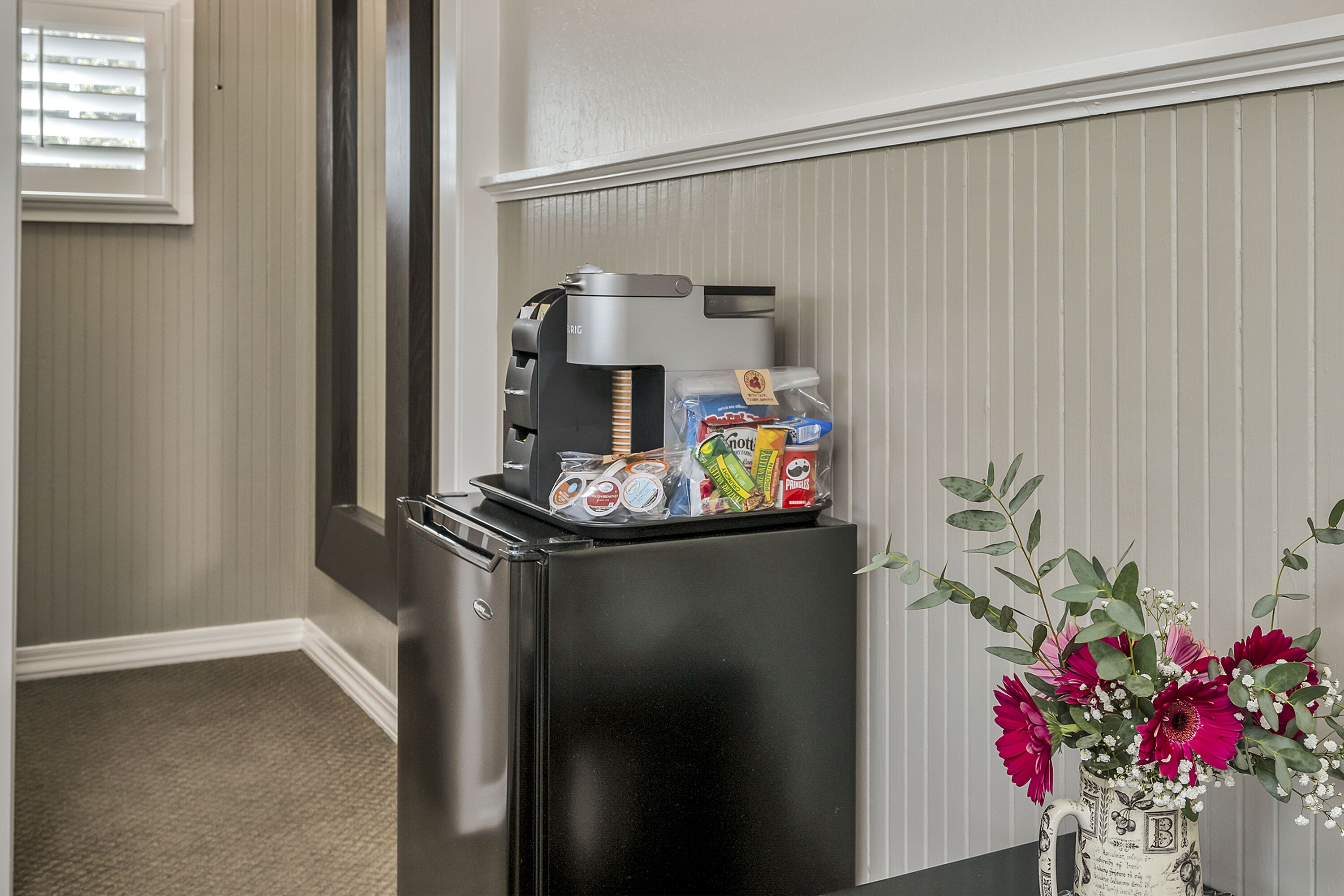 A black refrigerator with a coffee maker and a carton of milk on top.