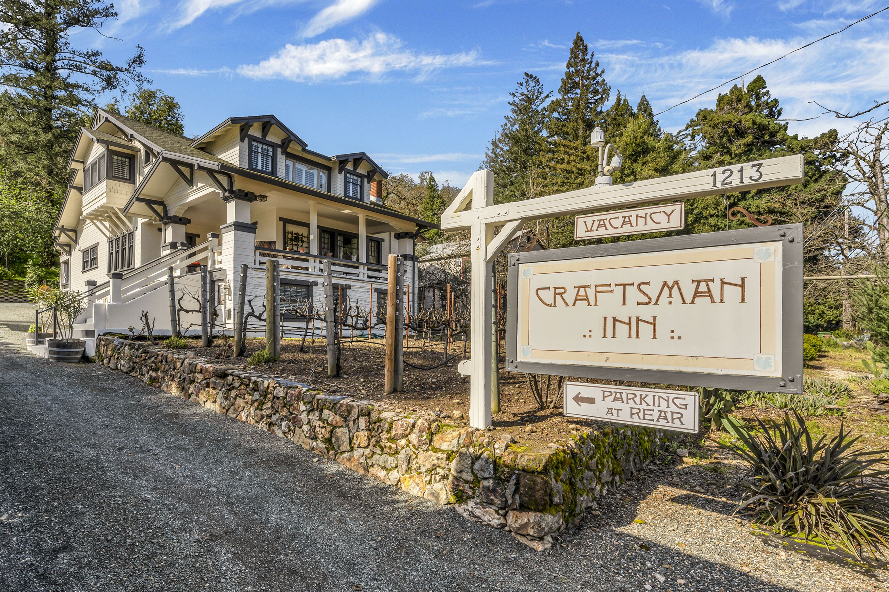 A Craftsman Inn with a stone wall and a sign indicating a vacancy.
