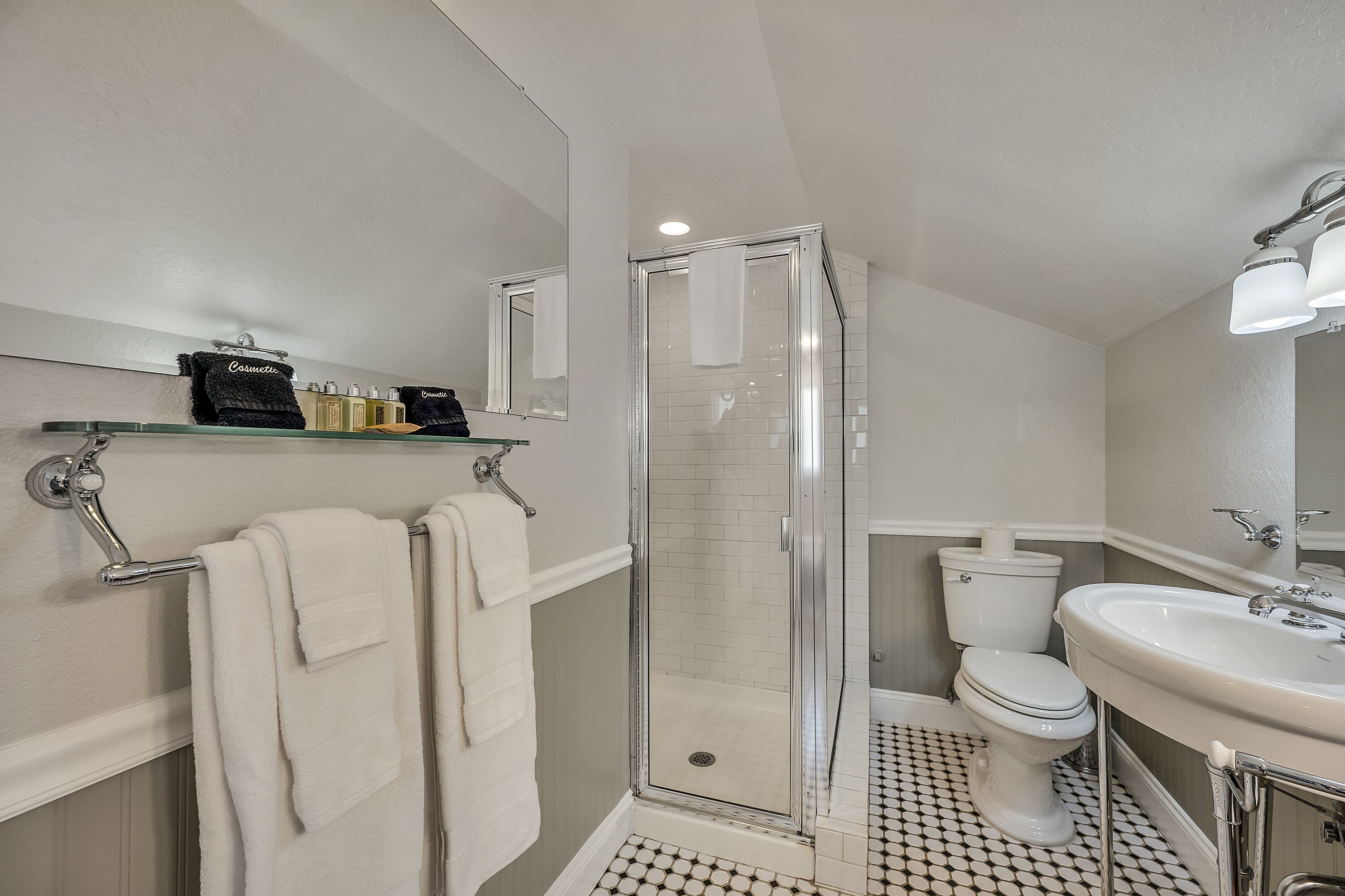Ein Badezimmer mit einer Duschkabine, Toilette, Waschbecken und einem Spiegel über dem Waschbecken.