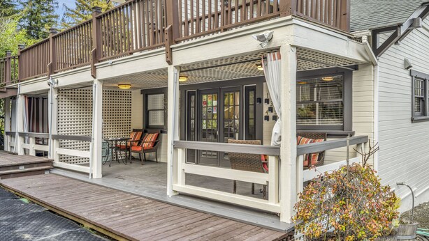 A two-story building with a covered porch, outdoor seating area, and a small garden.
