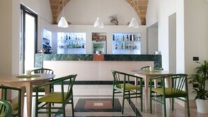 Un comedor con techo de ladrillo, una barra con una exhibición de botellas y sillas verdes.