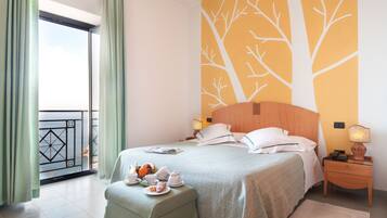 Ein Hotelzimmer mit Bett, Nachttisch, Fenster mit Vorhängen und einer Wand mit einem Baum-Wandbild.