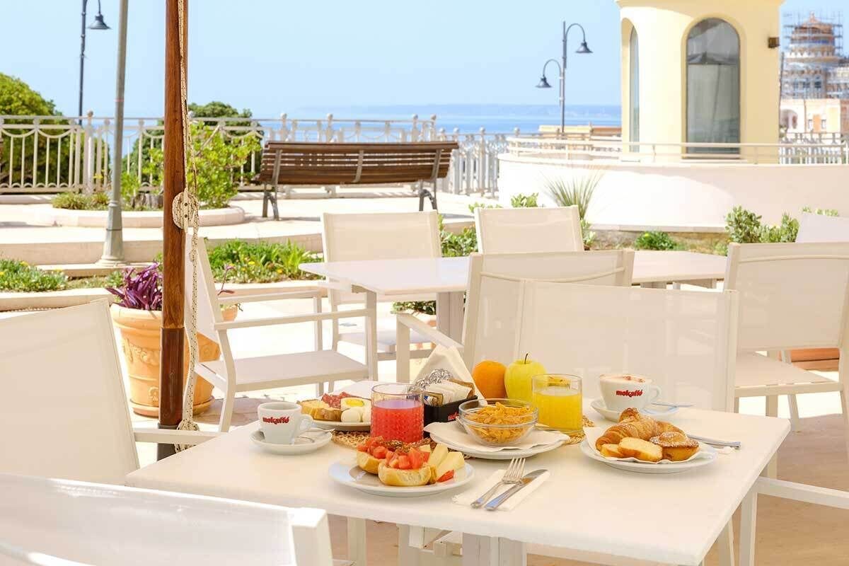 Une table dressée pour le petit-déjeuner, avec des chaises et une vue sur la mer.